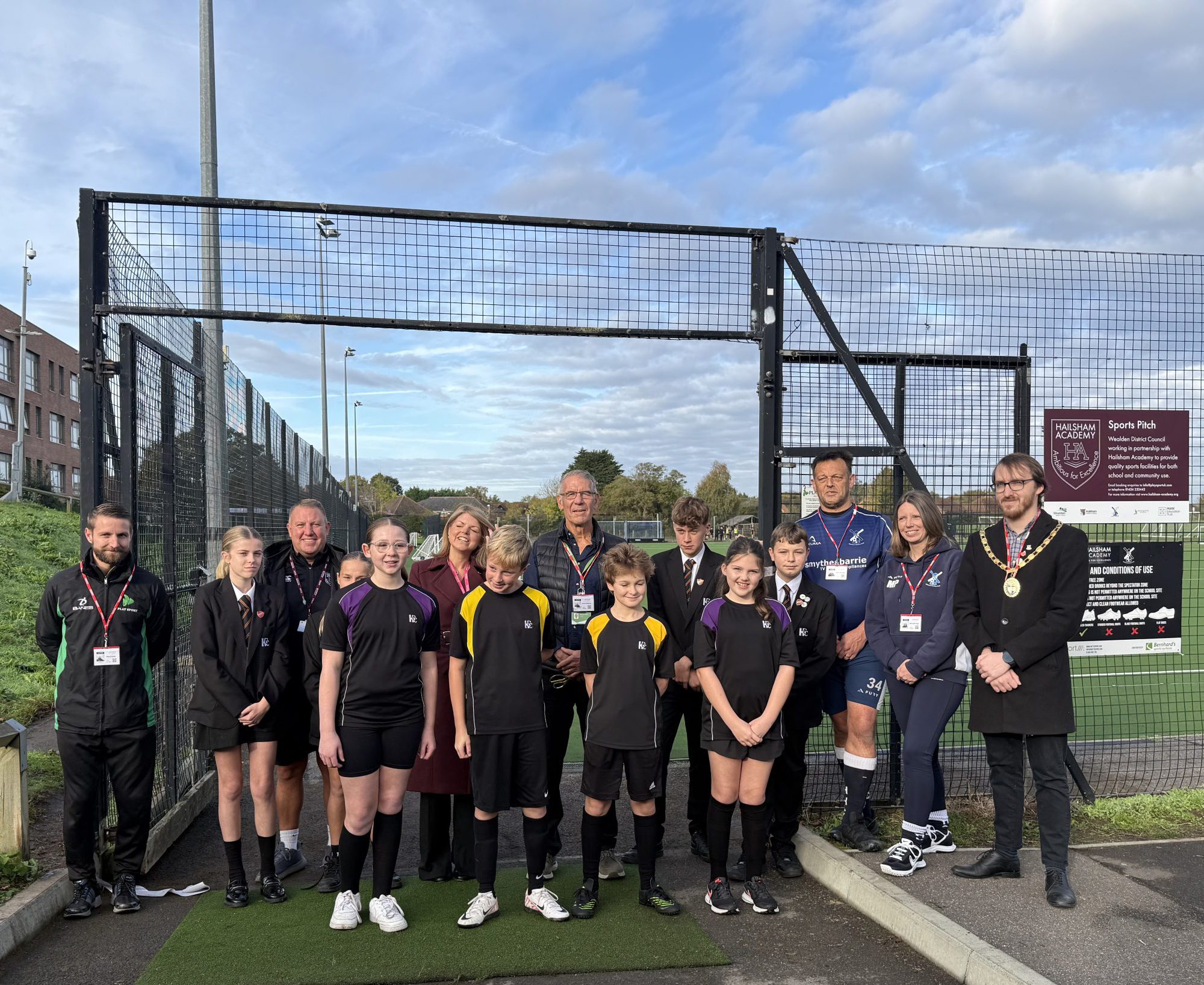 children standing in a group photo with councillor Kelvin Williams at the new renovated hockey pitch