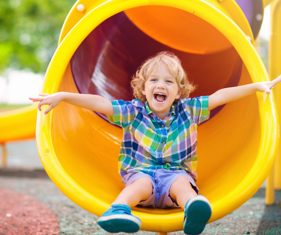 a child coming out the bottom of a yellow slide