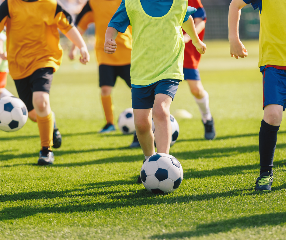 kids playing on artificial football pitch with a football