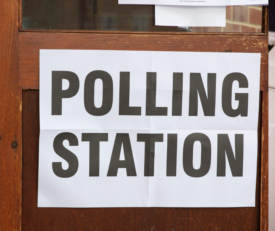 sign which reads polling station. the sign is on a brown wooden door frame