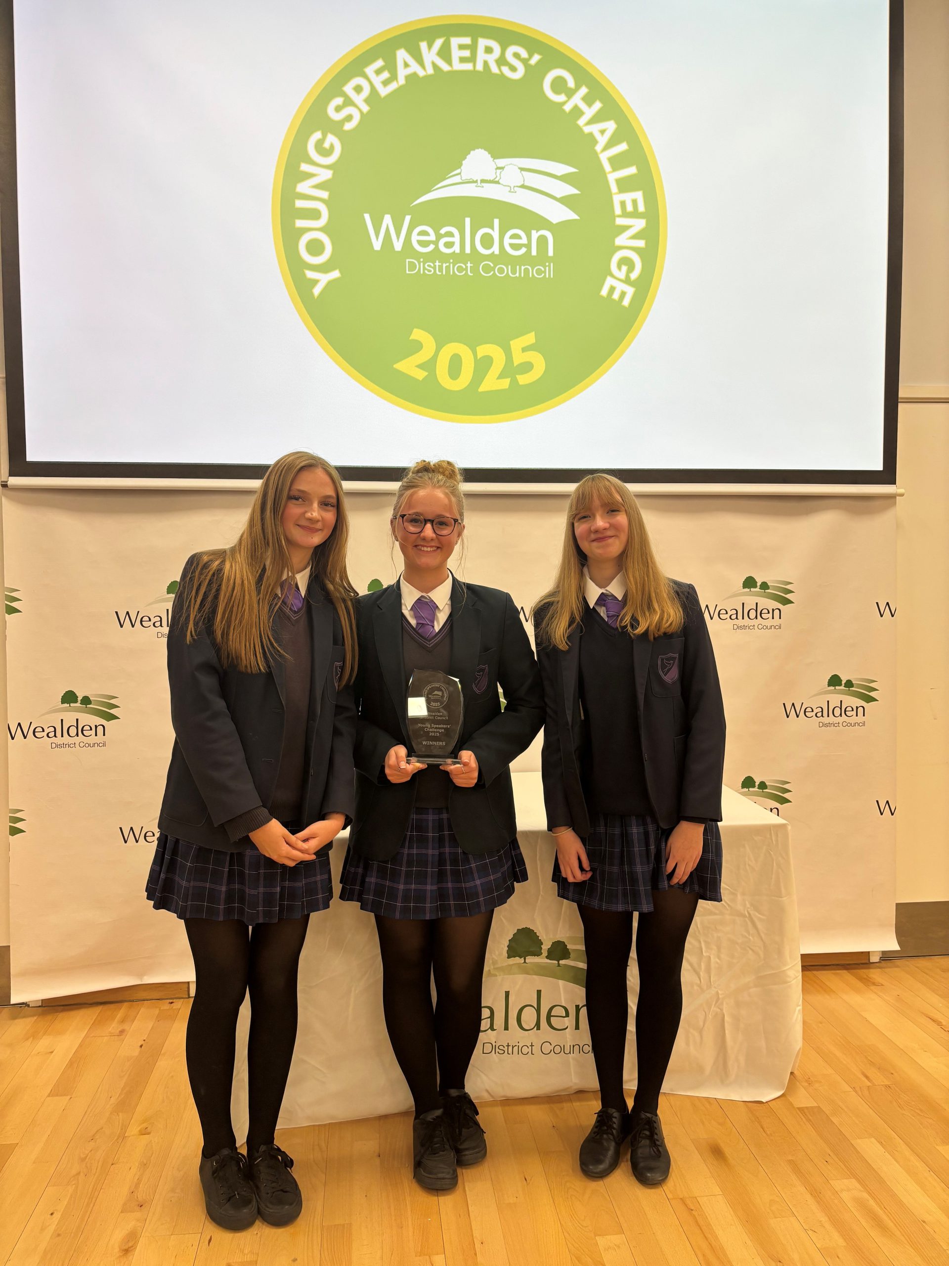 three people standing in a group holding an award